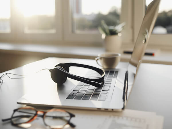 On-Demand Library Laptop opened with headphones and glasses on table