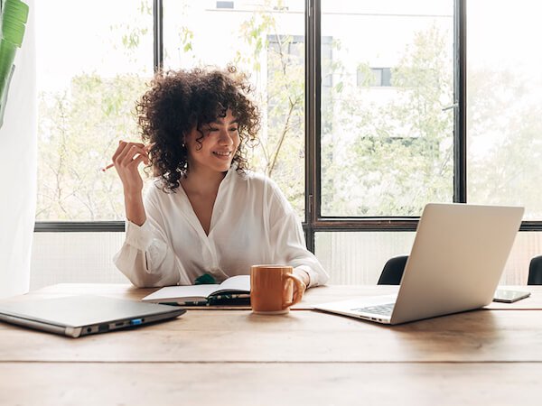 Woman working from home with laptop and taking notes